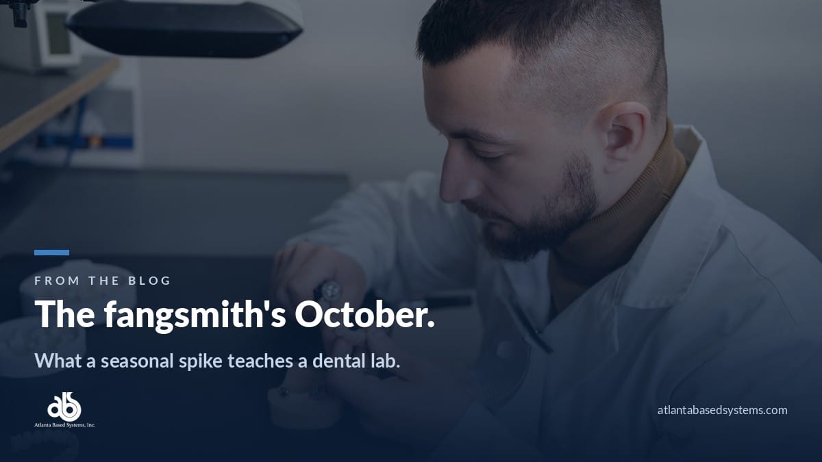 Dental technician in whites working a case at a dark bench, with the headline: the fangsmith's October.