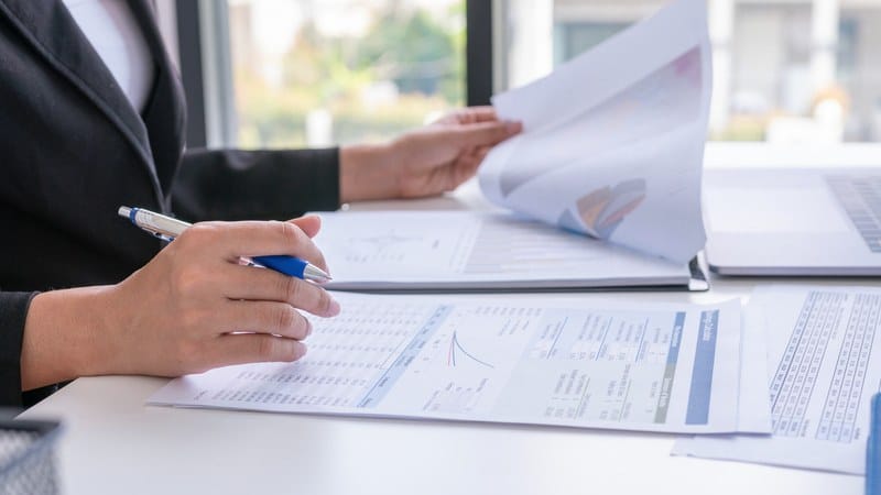 Two people comparing printed reports across a desk